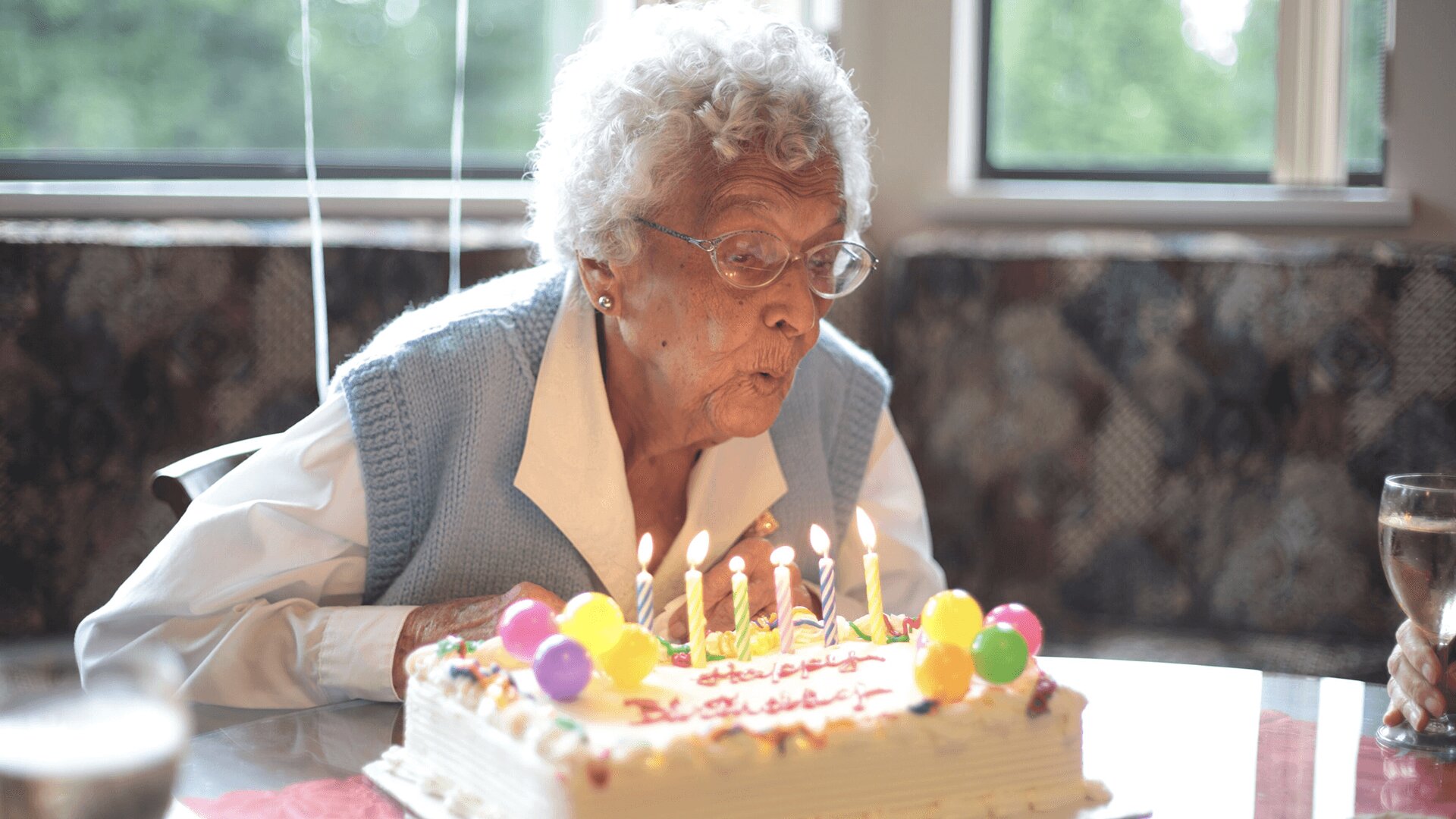 An elderly lady blowing candles on her birthday